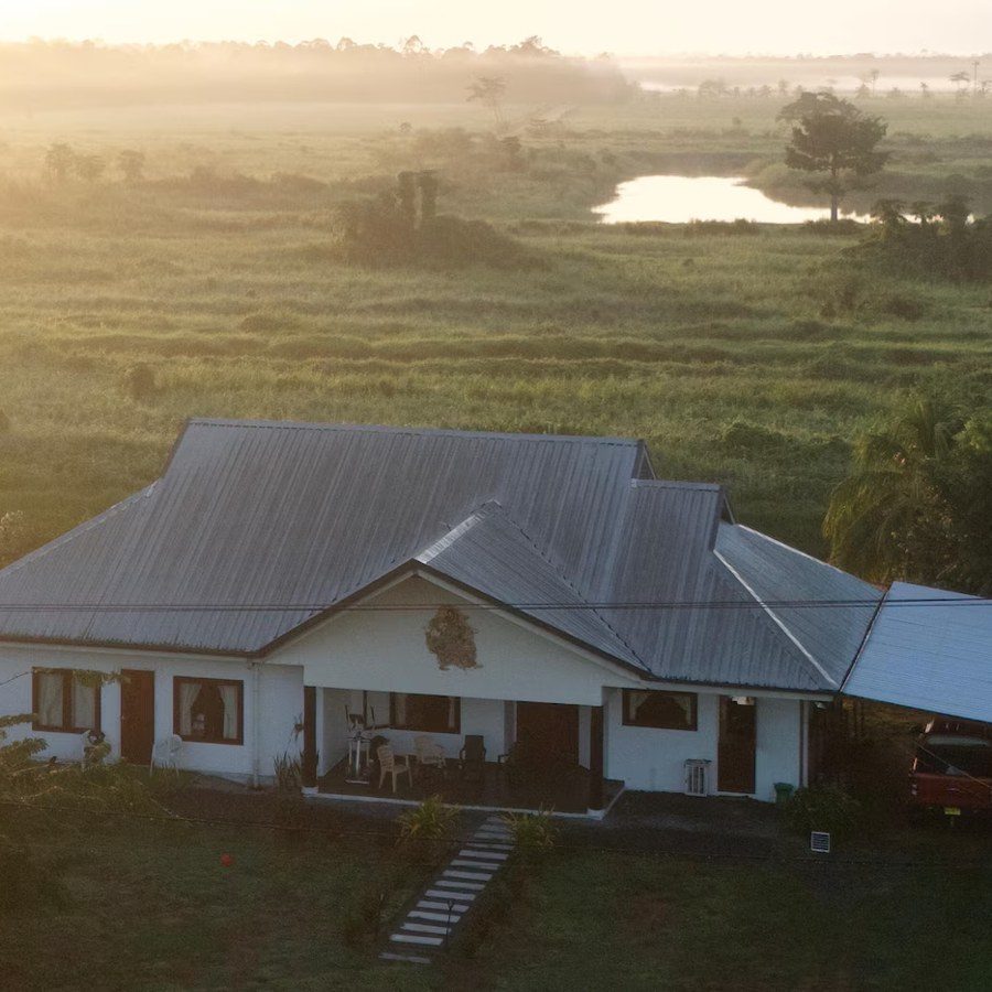 Villa Weltevreden: witte woning met veranda en carport in een mistig landschap bij zonsopkomst